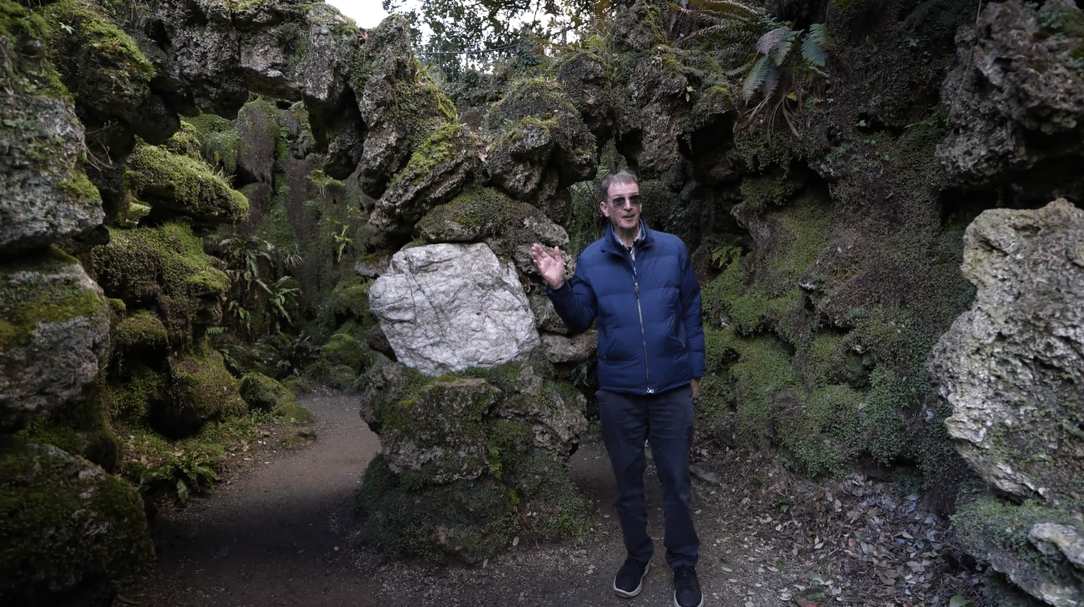 John Ducie, licensed tour guide Ireland, exploring a moss-covered rock grotto on a private guided garden tour in Ireland