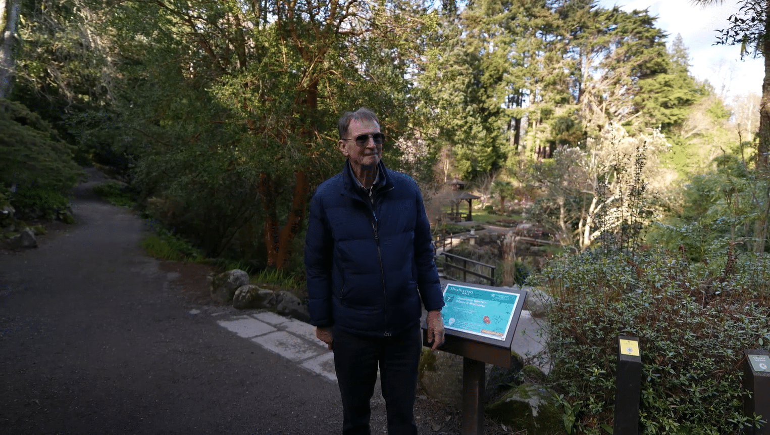 John Ducie, private garden tour guide Ireland, beside a woodland information board on a guided garden tour from Dublin