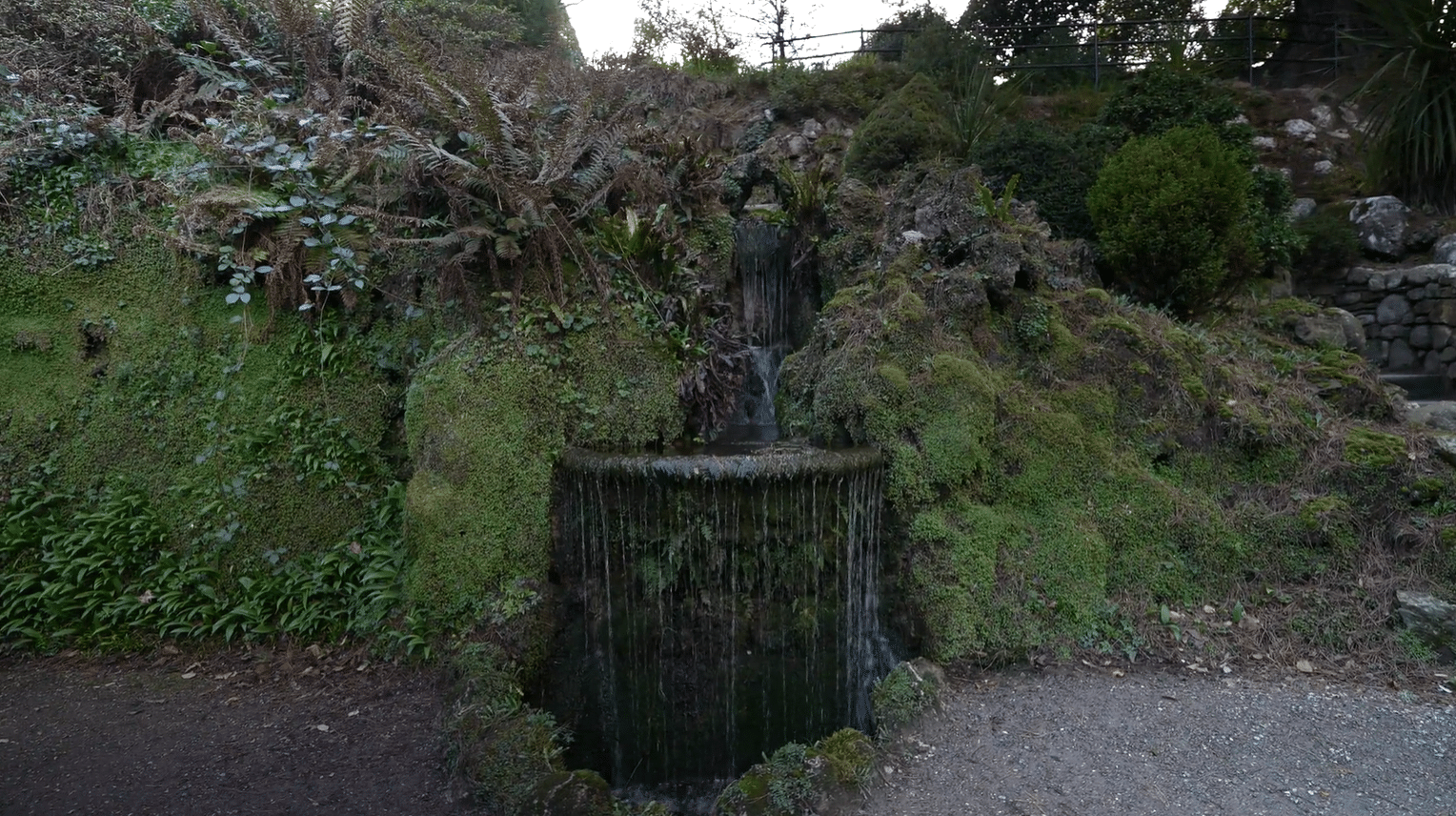 Cascading stream fountain flowing over moss-covered rocks in the grotto area of Powerscourt Gardens, County Wicklow, Ireland, visited on private garden tours from Dublin